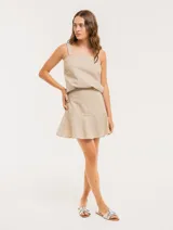 Falda corta color beige con rayas verticales blancas, corte evasé y volado en el ruedo.