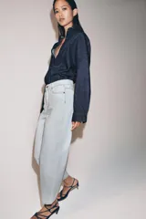 Jeans de tiro alto y silueta tapered, confeccionados en denim negro con costuras en tono contrastante. Cuenta con diseño de cinco bolsillos, trabillas para cinto y cierre frontal con cremallera y botón metálico.
