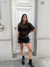 Remerón negro de encaje con mangas cortas, cuello redondo y corte holgado. Incluye un cinturón con apliques metálicos.