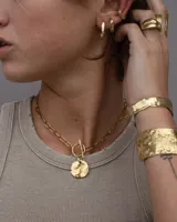 Pulsera tipo esclava abierta con diseño rústico y acabado irregular, fabricada en bronce y alpaca.