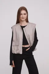 Chaleco color caqui con cierre frontal con cremallera, bolsillos con solapa y corte holgado.