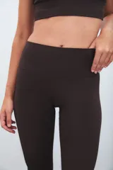 Calza deportiva de tiro alto color marrón, con diseño de perforaciones láser en la parte inferior de las piernas.