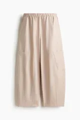 Pantalón cargo de color beige, con perneras estilo globo, cintura elástica y bolsillos laterales de parche.