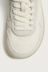 Zapatilla deportiva estilo barefoot fabricada en piel. Presenta un diseño de paneles combinados, puntera redondeada y ancha para mayor libertad de movimiento, plantilla OrthoLite extraíble y suela de goma fina en contraste.