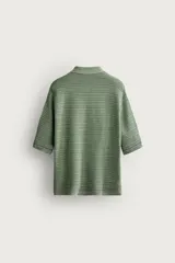 Polo de punto de algodón con textura acanalada, color verde militar, efecto lavado, cuello solapa, cierre frontal con botones y mangas cortas holgadas.