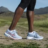 Championes de running Asics GT-1000 10, color celeste con detalles en rosa y blanco.