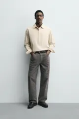 Camisa polo de corte relajado confeccionada en algodón, con estampado de rayas verticales finas. Presenta cuello solapa, cierre frontal parcial con botones, bolsillo plastrón en el pecho y mangas largas con puños abotonados.
