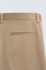 Pantalón chino de corte regular fit, confeccionado en tejido de algodón con elasticidad. Presenta bolsillos frontales, bolsillos traseros de vivo y cierre frontal con cremallera y botón.