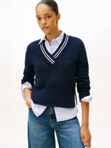 Sweater de punto color azul marino, con cuello en V ribeteado con dos franjas blancas. Presenta tejido trenzado (cableado) en el frente y puños y dobladillo acanalados.