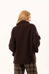 Tapado tipo poncho de color chocolate, confeccionado en tejido de paño, con cierre frontal completo metálico, cuello alto y bolsillos laterales.