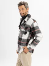 Sobrecamisa de franela con diseño a cuadros en tonos blanco, negro y detalles en rojo. Presenta cuello clásico, cierre frontal con botones y bolsillos en el pecho.