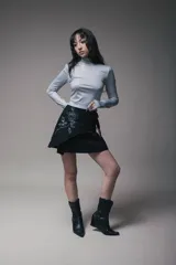 Minivestido negro con cuello alto y mangas largas. Presenta un drapeado lateral con lazos ajustables y un estampado de rosa en el frente.