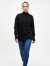 Buzo de punto color negro con cuello alto, mangas largas y puños acanalados. Presenta un diseño de corte recto con terminaciones acanaladas en el ruedo.