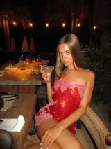 Vestido corto de lentejuelas rojas con detalles de encaje rosado en el escote y el ruedo, de corte recto y tirantes finos.