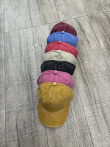 Set de gorros de béisbol de distintos colores con visera curva y botón superior.