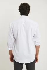 Camisa blanca de vestir, de manga larga con puños abotonados y cuello clásico.