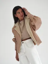 Campera de cuero color tostado con solapa amplia en corderito, calce oversize, mangas anchas ajustadas en el bajo y detalle de cuero trenzado en la parte delantera.