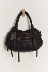 Cartera de cuero color negro con efecto lavado y desgastado, estilo vintage. Cuenta con múltiples bolsillos con cierre delantero, tiras colgantes y doble asa corta de mano.
