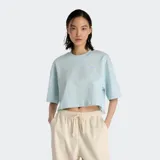 Remera celeste de corte cropped y mangas cortas, con logo de New Balance bordado en el pecho.