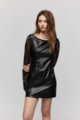 Vestido corto de símil cuero negro, de corte recto, escote amplio y sin mangas, combinado con mangas largas de encaje negro.