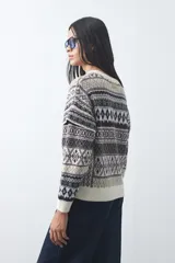 Sweater de punto con diseño jacquard de inspiración nórdica, cuello redondo y mangas largas. Presenta un patrón geométrico en tonos tierra, azul y blanco, con puños y ruedo acanalados.