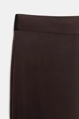 Pantalón flare de tiro alto confeccionado en tejido satinado color negro, con bajo en línea evasé y cierre frontal con cremallera oculta y gancho metálico.
