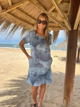 Vestido corto de lino celeste con estampado de flores abstractas en tonos azules y blancos, de manga corta y corte recto con bolsillos laterales.