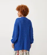 Cardigan abierto de punto con textura en relieve, mangas largas abullonadas y puños acanalados. Diseño holgado y versátil.