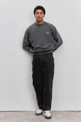 Buzo de cuello redondo en color gris oscuro con efecto lavado, manga larga y calce holgado. Presenta una pequeña estampa minimalista en el pecho.