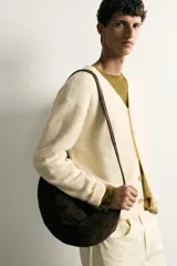 Cárdigam relaxed fit de punto tejido en color beige claro, con cuello en V, manga larga, acabados en rib y cierre frontal de botonadura con botones en tono carey.