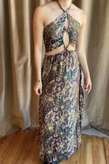 Vestido largo de estilo boho con estampado paisley en tonos tierra, naranjas y azules. Presenta un top tipo halter con espalda descubierta y elástica, y una falda larga con caída fluida y elástico en la cintura.