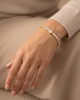 Pulsera de acero con baño de oro, compuesta por una cadena de eslabones engastados con circonias y un dije central circular de mayor tamaño con circonia.