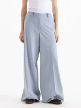Pantalón de vestir tiro alto color celeste, de corte wide leg y largo hasta el suelo, con bolsillos delanteros decorados con volados tableados y bolsillos ojal en la espalda.
