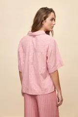 Blusa celeste de manga corta con cuello camisero y escote en V, confeccionada en tejido liviano con textura sutil y estampado de lunares.