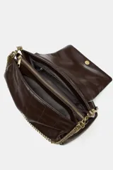 Bolso bandolera de hombro en color marrón, con diseño acolchado de costuras verticales. Cuenta con una cadena metálica dorada y un asa de mano superior. El cierre principal es mediante botón imantado.
