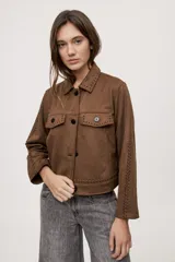 Campera negra de efecto gamuzado con cuello camisero, cierre frontal de botones, bolsillos plaqué en el pecho y detalles de costuras decorativas y calados.