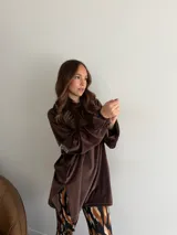 Canguro negro de terciopelo, de corte oversize y manga larga, con capucha y detalle de parche bordado en la manga.