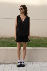 Blusa negra sin mangas de microtul con escote en V drapeado y corte holgado. 