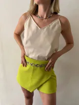 Short pollera color lima, confeccionado en crepé con spandex, con diseño cruzado en el frente.