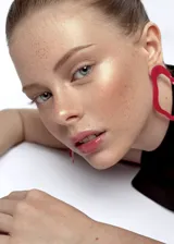 Par de aros colgantes de acrílico rosa con forma ovalada y detalle de torsión en el centro.