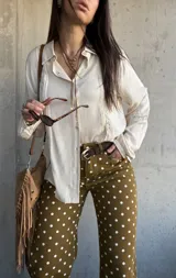 Camisa de manga larga color marfil con detalles de encaje y botones frontales.