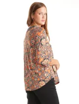 Blusa de seda fría estampada con motivo floral paisley en tonos naranja, negro y beige. Cuello a la base con escote en V y patrón geométrico. Corte holgado con fruncido bajo el pecho y mangas tres cuartos. Ruedo con aberturas laterales y terminación redondeada.