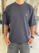 Remera oversize de tejido texturizado en color verde militar, con cuello redondo y mangas cortas. Presenta un pequeño bordado blanco en el pecho.