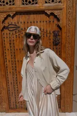 Camisa de lino negra con bordados dorados en forma de árbol o palmera estilizada. Presenta cuello camisero, botones frontales dorados y pliegues verticales en la parte inferior delantera.