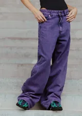Jean de corte oversized y tiro medio-alto, confeccionado en denim de color violeta con diseño de cinco bolsillos y cierre frontal con botón y cremallera.