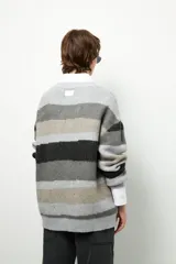 Sweater de punto con rayas horizontales en tonos beige, marrón y borgoña. De corte amplio, cuello redondo y mangas largas.