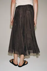 Falda midi de tiro medio de la colección ZARA Woman, confeccionada en mezcla de lyocell con acabado fluido y bajo en línea evasé. Cuenta con forro interior a tono y cierre lateral con cremallera oculta.