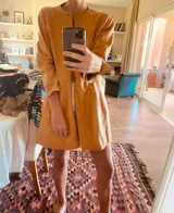 Tapado camel de cuero ovino con cuello clásico, cierre frontal con botones, bolsillos laterales y corte a la rodilla. Diseño slouchy y cómodo.