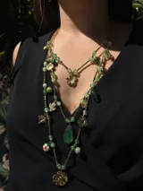 Collar largo de tres vueltas elaborado en acero, compuesto por una combinación de piedras naturales azules y dijes metálicos dorados con formas de flores y hojas.