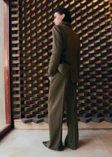 Pantalón de vestir verde militar, de corte recto y tiro alto, con bolsillos laterales y raya central marcada.
